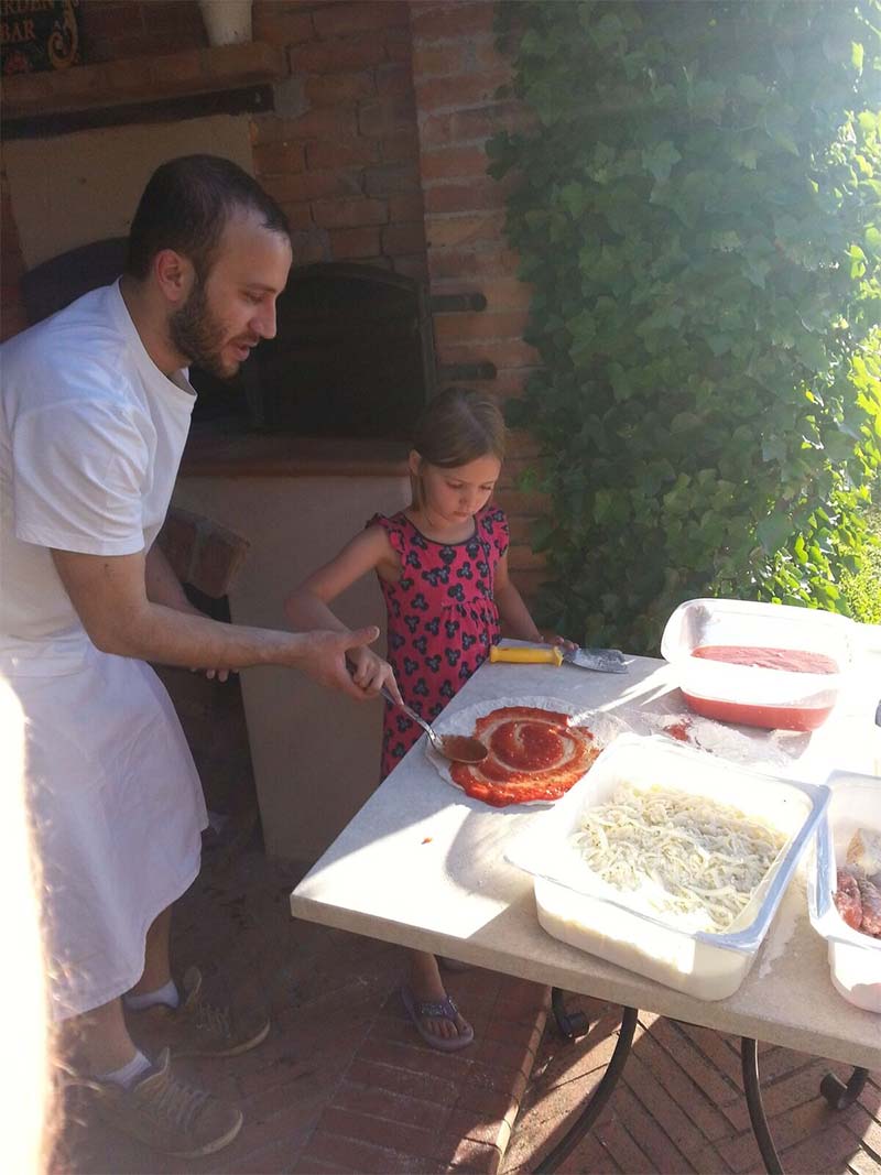 Chef helping child make pizza
